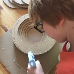 a young boy is making a sculpture out of cardboard