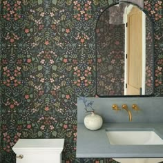 a bathroom with floral wallpaper and a white sink in front of a mirror on the wall