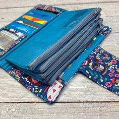 several wallets are stacked on top of each other, one is blue and the other has multicolored flowers