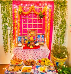 a table topped with lots of food next to a wall covered in vines and garlands