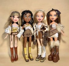 four dolls are standing next to each other in different outfits and boots, one is holding a purse