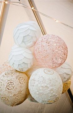 several white and pink decorative balls hanging from a string with lights in the back ground