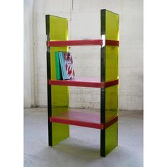 a green shelf with red and black shelves on it's sides, in front of a white wall