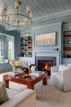 a living room filled with furniture and a fire place under a chandelier in front of a fireplace