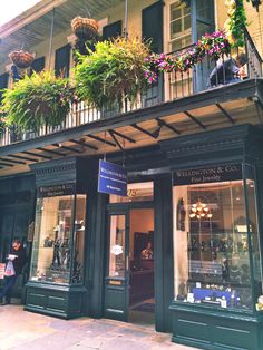 a storefront with flowers hanging from it's balconies