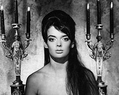 a black and white photo of a woman with long hair standing in front of candles