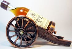 a bottle of wine sitting on top of a wooden cart with wheels and leather straps