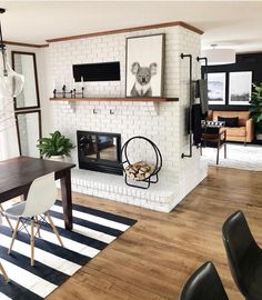 a living room with white brick fireplace and black chairs