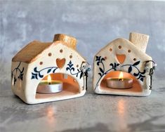 two small ceramic houses with candles in them