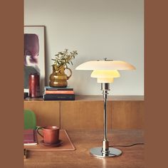 a table lamp sitting on top of a wooden table next to a vase and cup