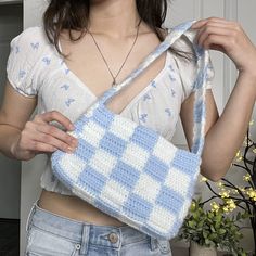 a woman is holding a crocheted purse