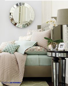 a living room with a couch, mirror and lamp on the side table in front of it