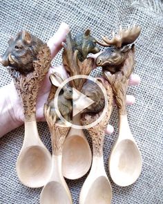 wooden spoons with carved animals on them are being held by someone's hand