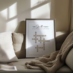 a framed poster sitting on top of a couch next to pillows and a blanket in front of a window