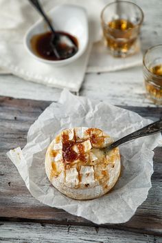 some food is sitting on a piece of wax paper next to glasses and a spoon