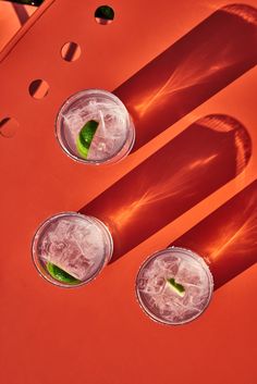 two glasses filled with drinks sitting on top of a red table