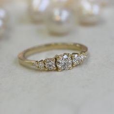 a three stone diamond ring sitting on top of a white table next to pearl beads