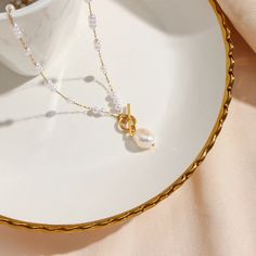 Elevate your look with the Pearl Drop Gold Necklace. The delicate pearl beads add a touch of elegance and sophistication to any outfit. Make a statement and exude confidence with this timeless piece. DETAILS & SIZE Finish: 18K gold plate Materials: Stainless Steel; Synthetic Pearl; Freshwater Pearl (pendant) Measurements: Pendant: 11x7.5mm; Chain: 21" Toggle pendant clasp Waterproof, tarnish-resistant, and nickel free Shop the Pearl Passion collection! Or shop our Necklaces for more options to layer this with! Pearl White Pearl Clavicle Chain Necklace, Pearl White Pearl Chain Necklace In Gold Plated, Gold Pearl Necklace With Pearl Pendant, Gold Plated Pearl White Necklace With Pearl Chain, Pearl White Gold-plated Pearl Chain Necklace, Feminine Gold Pearl Chain Necklace, Elegant White Chain Necklace With Pearl Drop, Gold Feminine Pearl Pendant Necklace, Feminine Gold Pearl Pendant Necklace