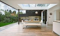 an outdoor dining area with glass walls and floor to ceiling windows, overlooking the garden