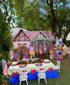 an outdoor table set up for a party with fairy garden decorations on the lawn and in front of it