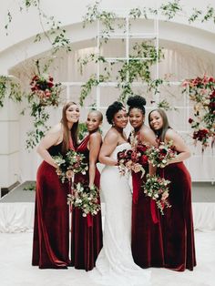 a group of women standing next to each other in front of a white building with red flowers