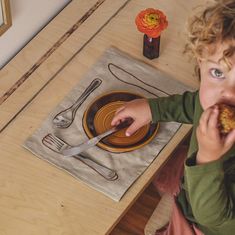 a little boy sitting at a table eating food