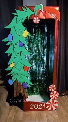 a cardboard christmas tree with candy canes on the bottom and an ornament hanging from it