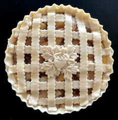 an apple pie with latticed crust on a black surface