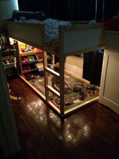 there is a bunk bed with a train track on the floor and toys underneath it