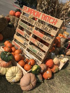 pumpkin patch sale sign surrounded by wooden crates and hay bales on the side of the road