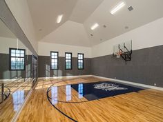 an indoor basketball court with hard wood floors and white walls, surrounded by black framed windows