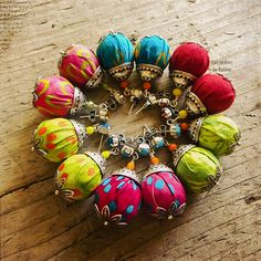 a bunch of balls are arranged in a circle on a wooden table with beads and charms