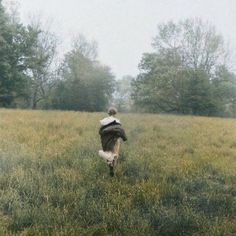 a person walking through a field with trees in the background