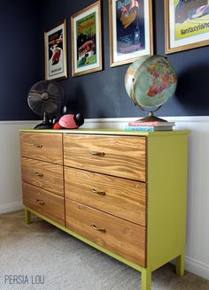 a dresser with pictures on the wall and an earth globe on top in front of it