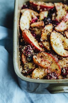 a casserole dish with apples and cranberries in it on a blue cloth