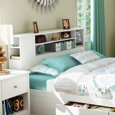 a white bed sitting next to a window with lots of bookshelves on top of it