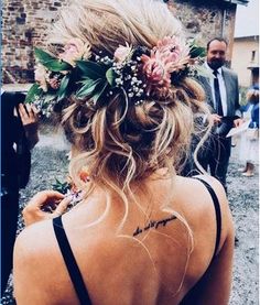 the back of a woman's head with flowers in her hair and other people standing around