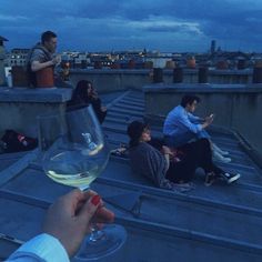 people are sitting on the roof drinking wine