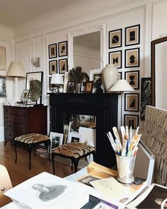 a living room filled with lots of furniture and pictures on the wall next to a fire place