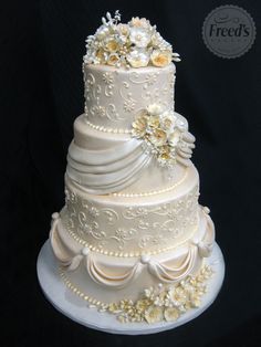 a three tiered wedding cake with white flowers on the top and sides, sitting on a plate