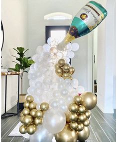 a champagne bottle is being poured into some white and gold balloons in the shape of a christmas tree