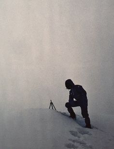 a man climbing up the side of a snow covered mountain with his skis on