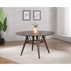 a table with two vases on it in front of a white rug and potted plant