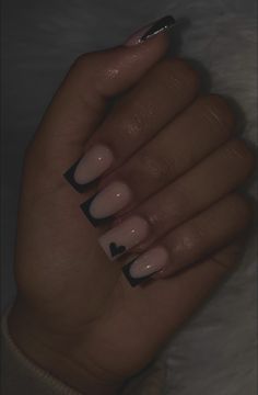 a woman's hand with black and white manicures on it, holding her nails