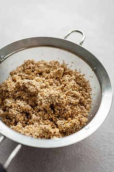 a metal strainer filled with food sitting on top of a white counter next to a knife