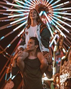 a man carrying a woman on his shoulders in front of a ferris wheel