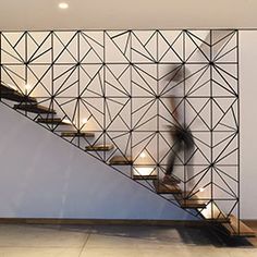 a person walking up some stairs in front of a wall with geometric designs on it