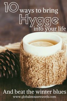 a cup of coffee sitting on top of a wooden table next to a pine cone