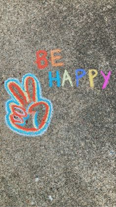 the sidewalk has been decorated with chalk to spell out be happy and two fingers are drawn on it