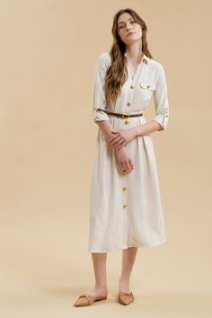 Get ready to stand out in the Monica Midi Dress, featuring a collared neckline and button down front. With gold buttons and hardware, this dress comes complete with a belted waist and pintuck details for a flattering silhouette. The long sleeves with cuff and tab detail, along with the midi length, make this a versatile shirt dress for any occasion. Plus, it even has pockets for added convenience! Formal Button-up Dresses With Belted Cuffs, Elegant Beige Midi Length Belted Dress, Elegant Cream Shirt Dress For Daywear, Chic Belted Dress With Buttons, Elegant Beige Dress With Belt, Spring Formal Collared Belted Dress, Elegant Cream Long Sleeve Shirt Dress, Elegant Long Sleeve Cream Shirt Dress, Cream Collared Dress For Work